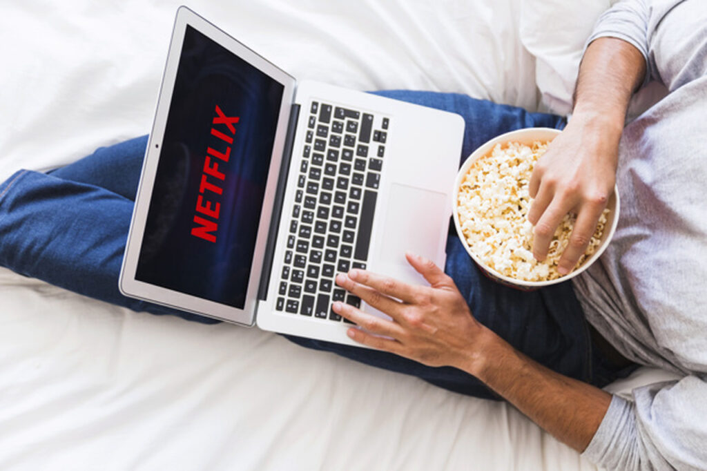 mezczyzna oglada Netlix na laptopie je popcorn
