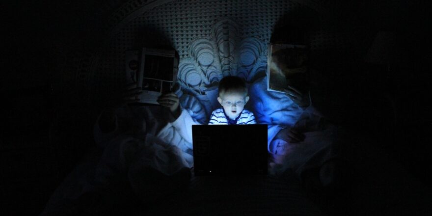 Dziecko siedzące przed laptopem w nocy